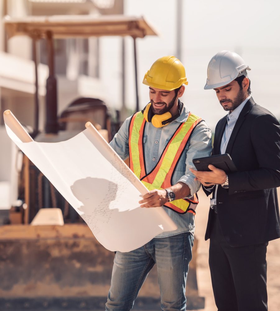 Civil engineer and construction worker manager holding digital tablet and blueprints , talking and planing about construction site.  Cooperation teamwork concept.